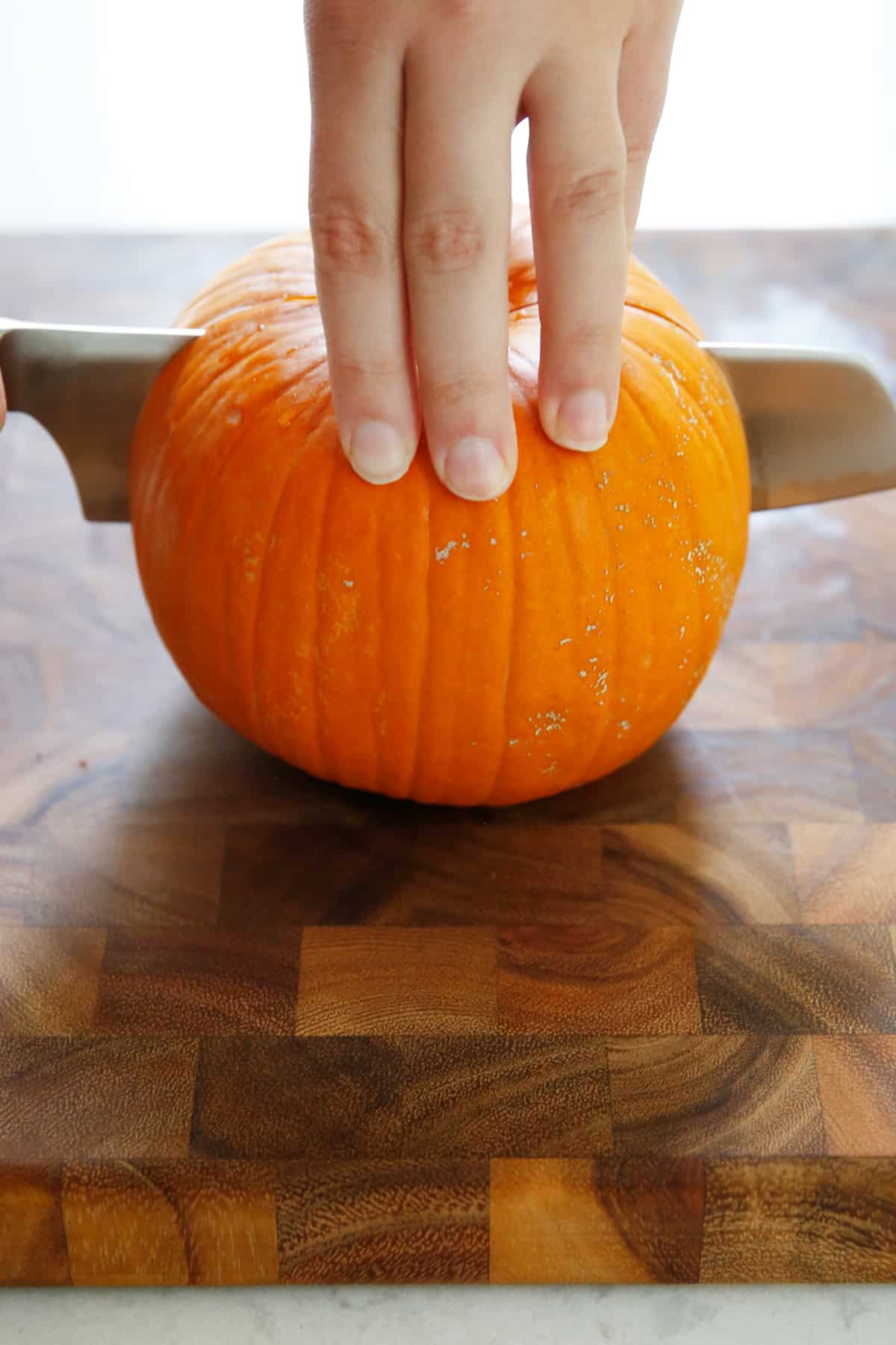 cutting through a fresh pumpkin for homemade pumpkin puree