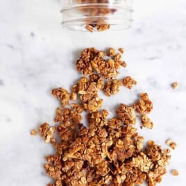 Gluten free granola spilling from a glass jar.