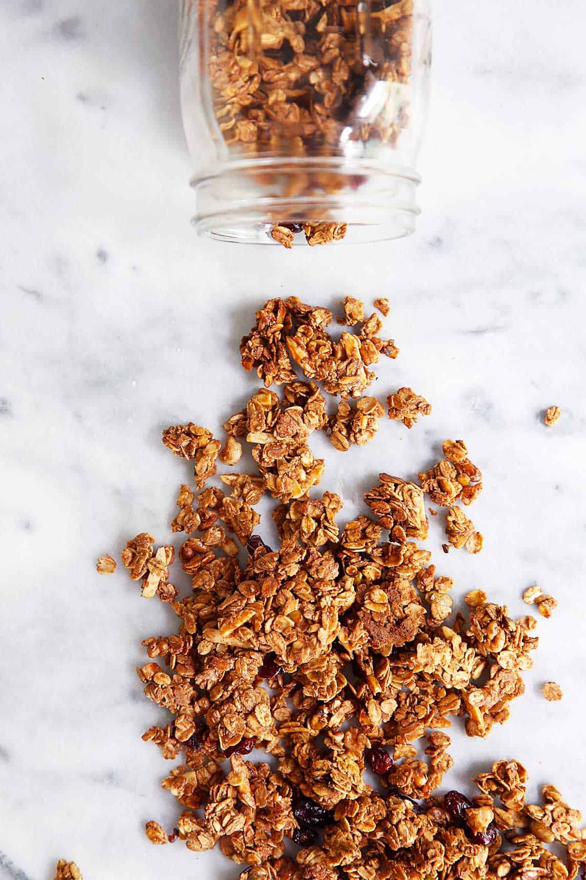 Gluten free granola in a jar spilling onto a counter. 