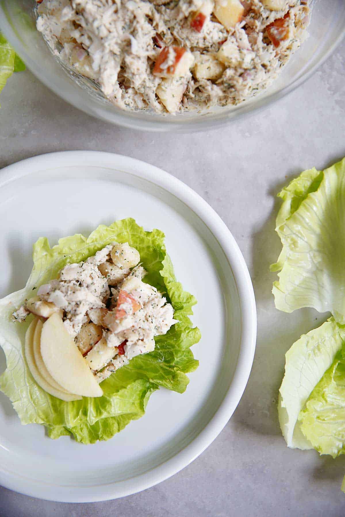 Apple dill chicken salad on a lettuce leaf topped with apple slices.