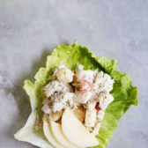 Apple dill chicken salad on a lettuce leaf with apples slices.