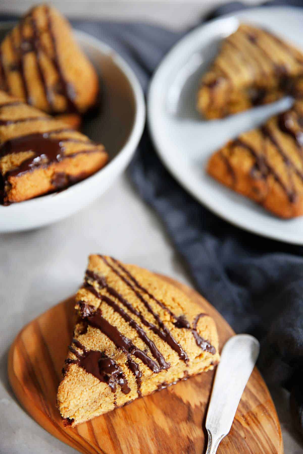 A gluten-free pumpkin scone with drizzled chocolate on it!