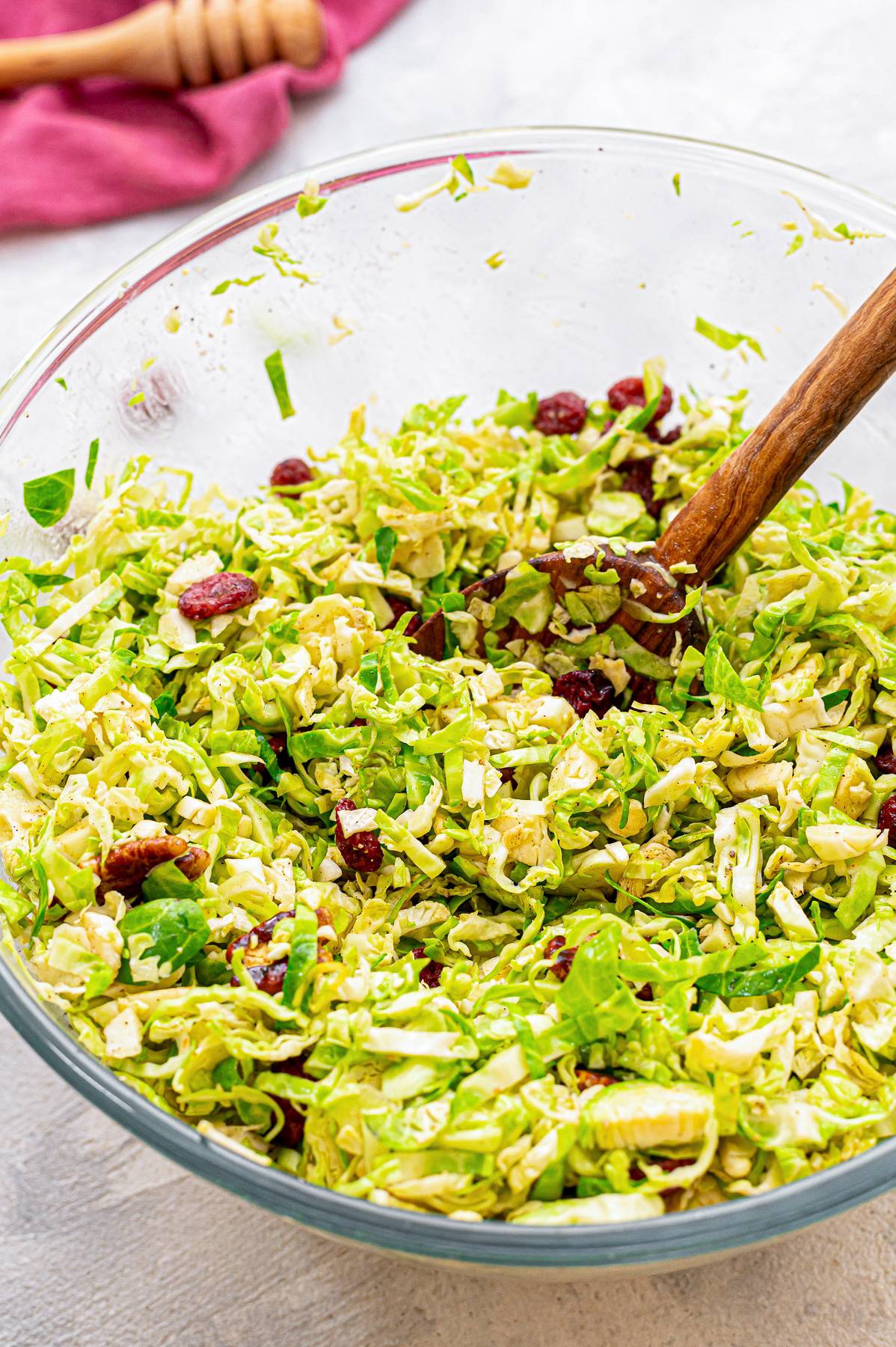 Tossed brussel sprout slaw in a bowl with cranberries and pecans.