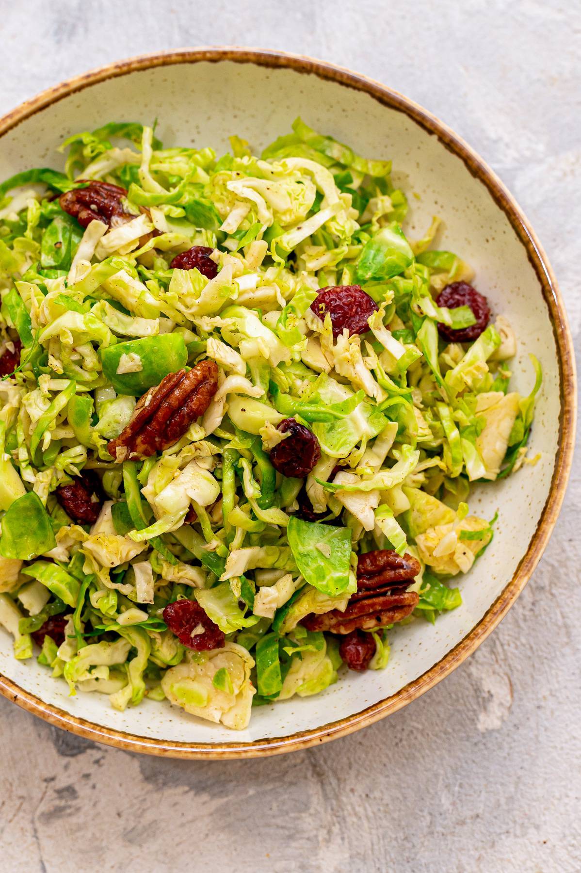 Brussels sprout slaw in a bowl with cranberries and pecans.