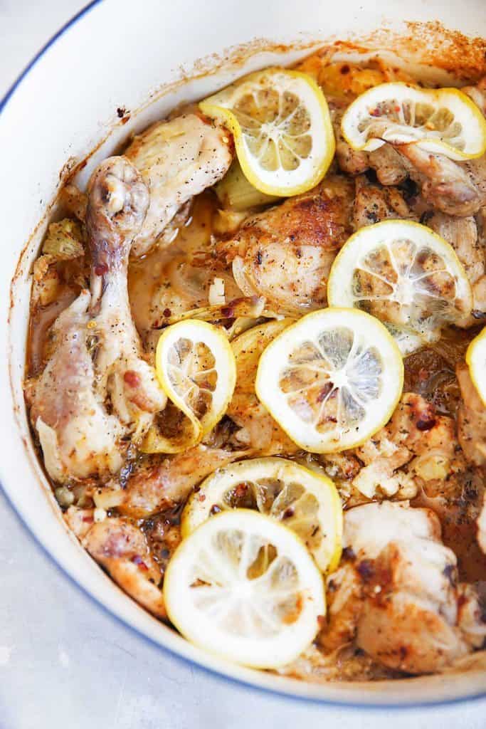 overhead of a dutch oven filled with cooked chicken and lemon.