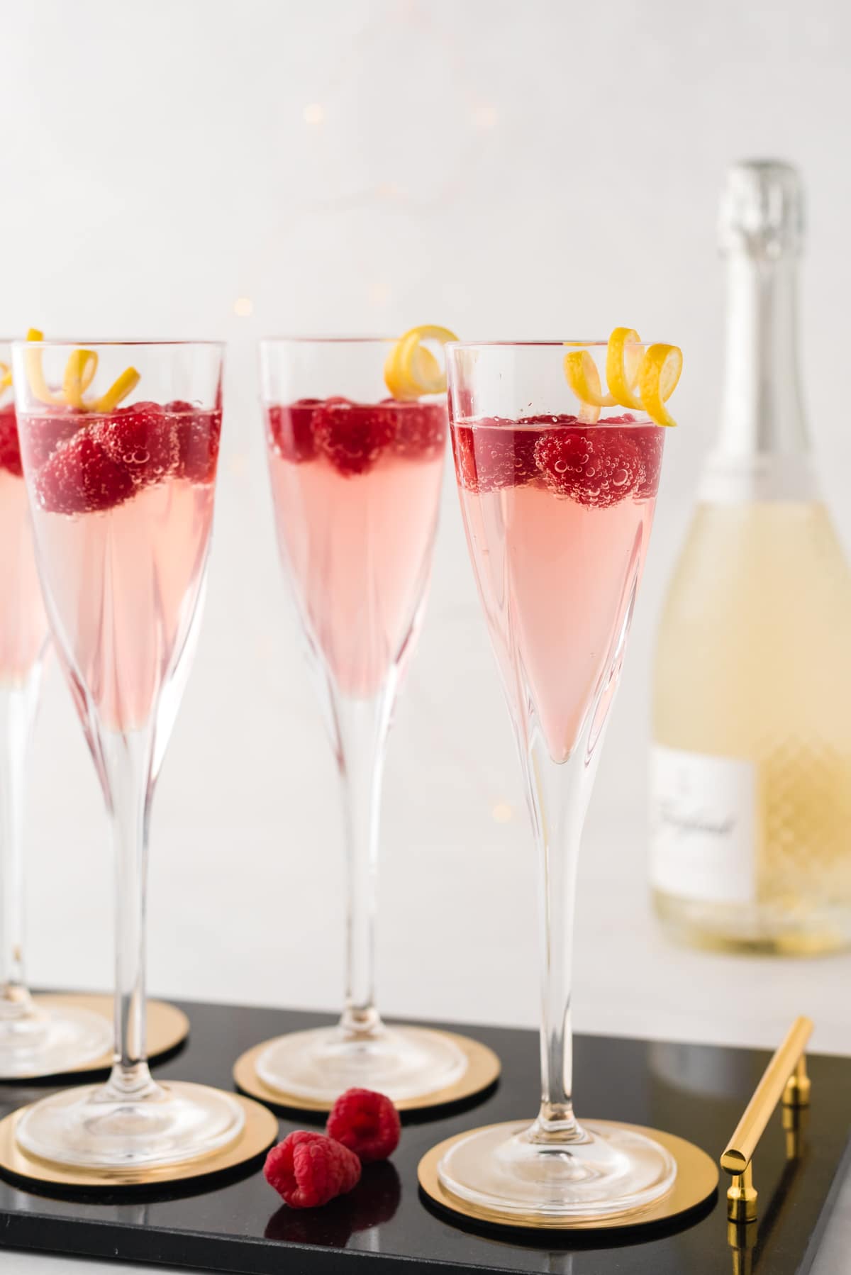 Champagne glasses with raspberries and a lemon twist.