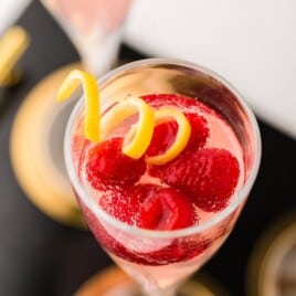 French kiss cocktail with raspberries and a lemon twist.