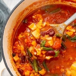 Rustic Tomato Soup with Veggies in a pot with a spoon in it.