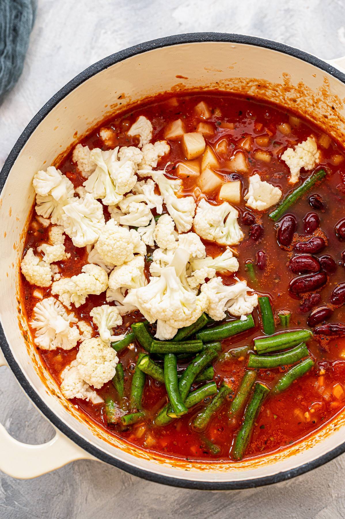 Veggies in a tomato broth in a pot.