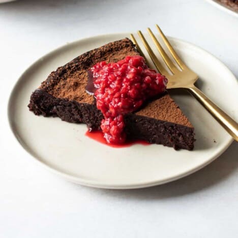 A slice of Paleo Flourless Chocolate cake with a quick raspberry sauce.