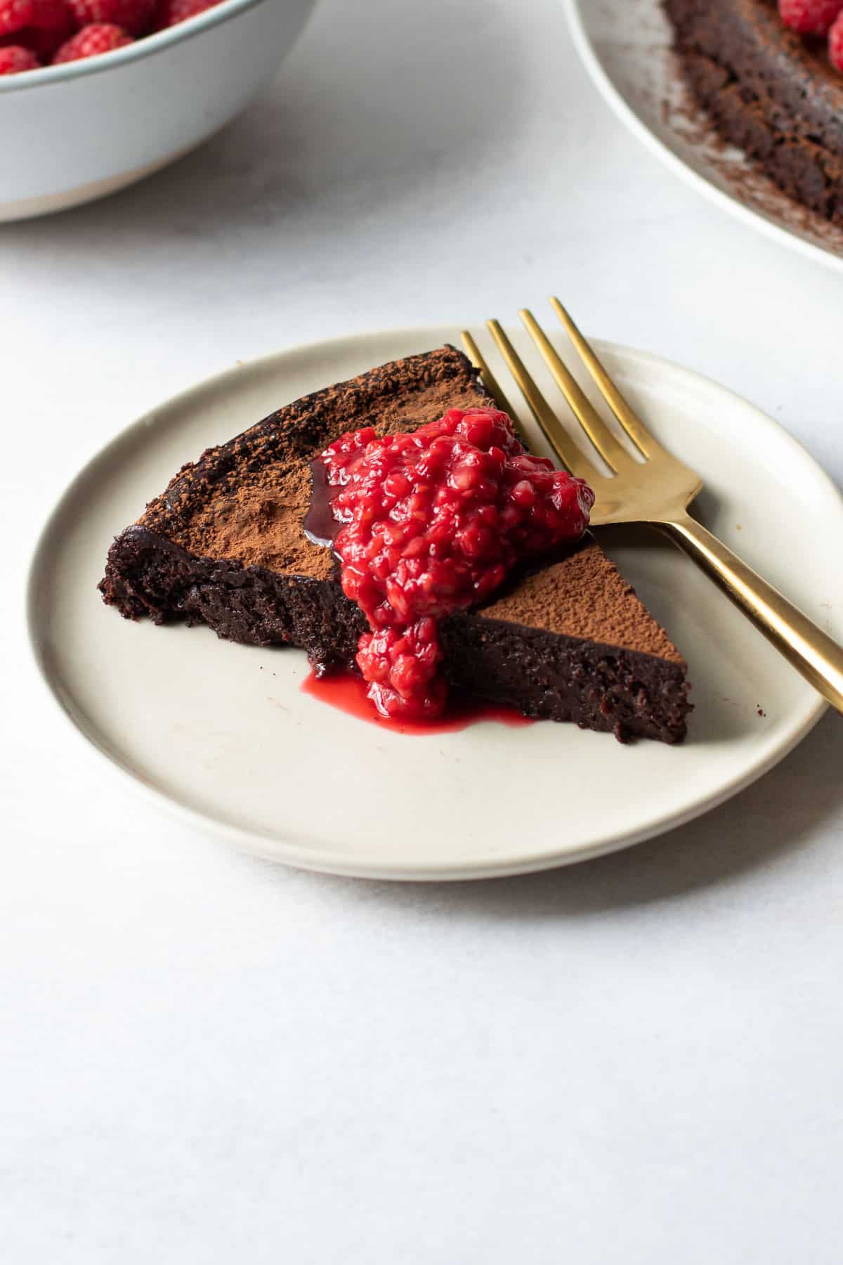 A slice of Paleo Flourless Chocolate cake with a quick raspberry sauce.