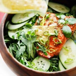 Dressing being poured over salmon salad.