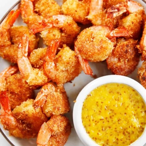 Healthy coconut shrimp on a plate with orange sauce.