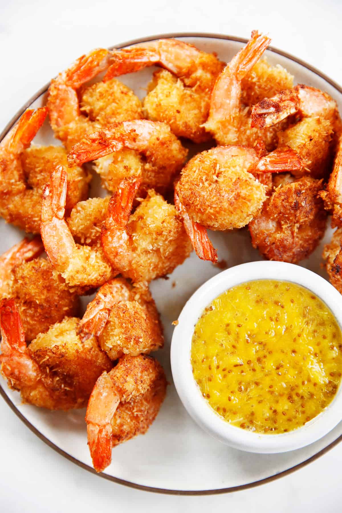 Healthy coconut shrimp on a plate with orange sauce.