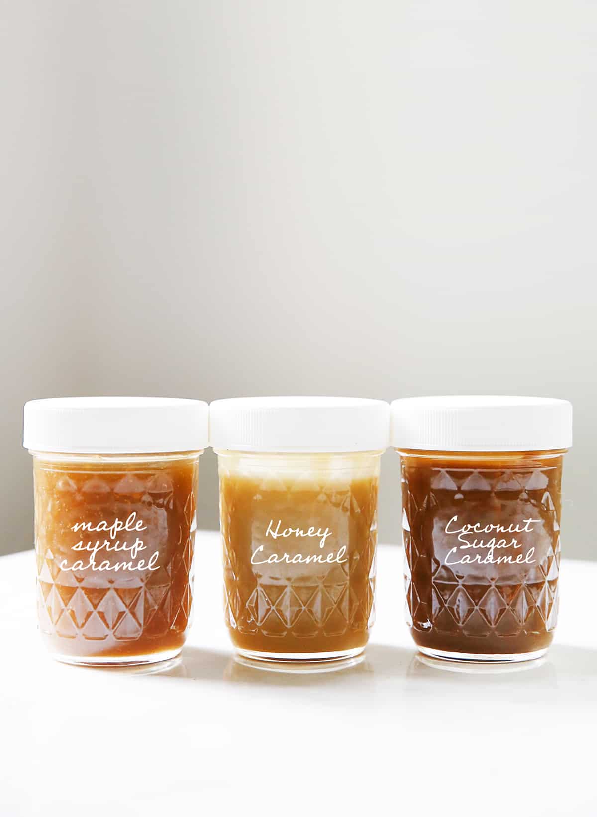Three jars of homemade caramel stand in a row.