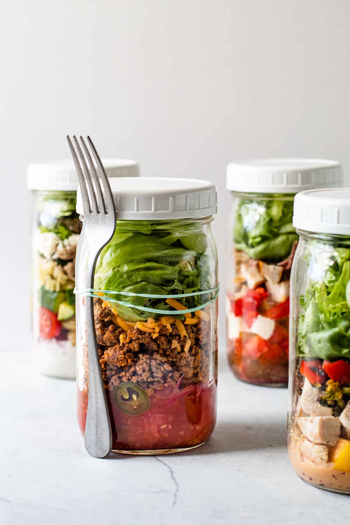 Mason jar salads with a fork attached to it.