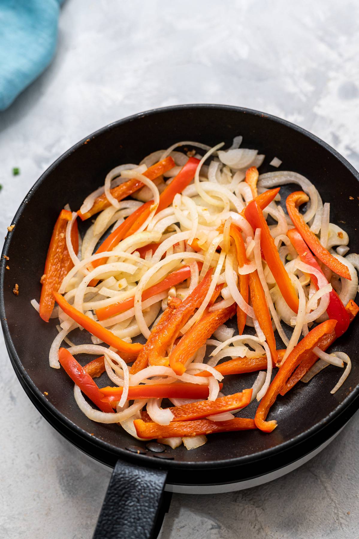 Onions and peppers in a saute pan.