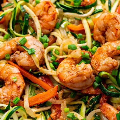 A close up view of shrimp and noodles with veggies.