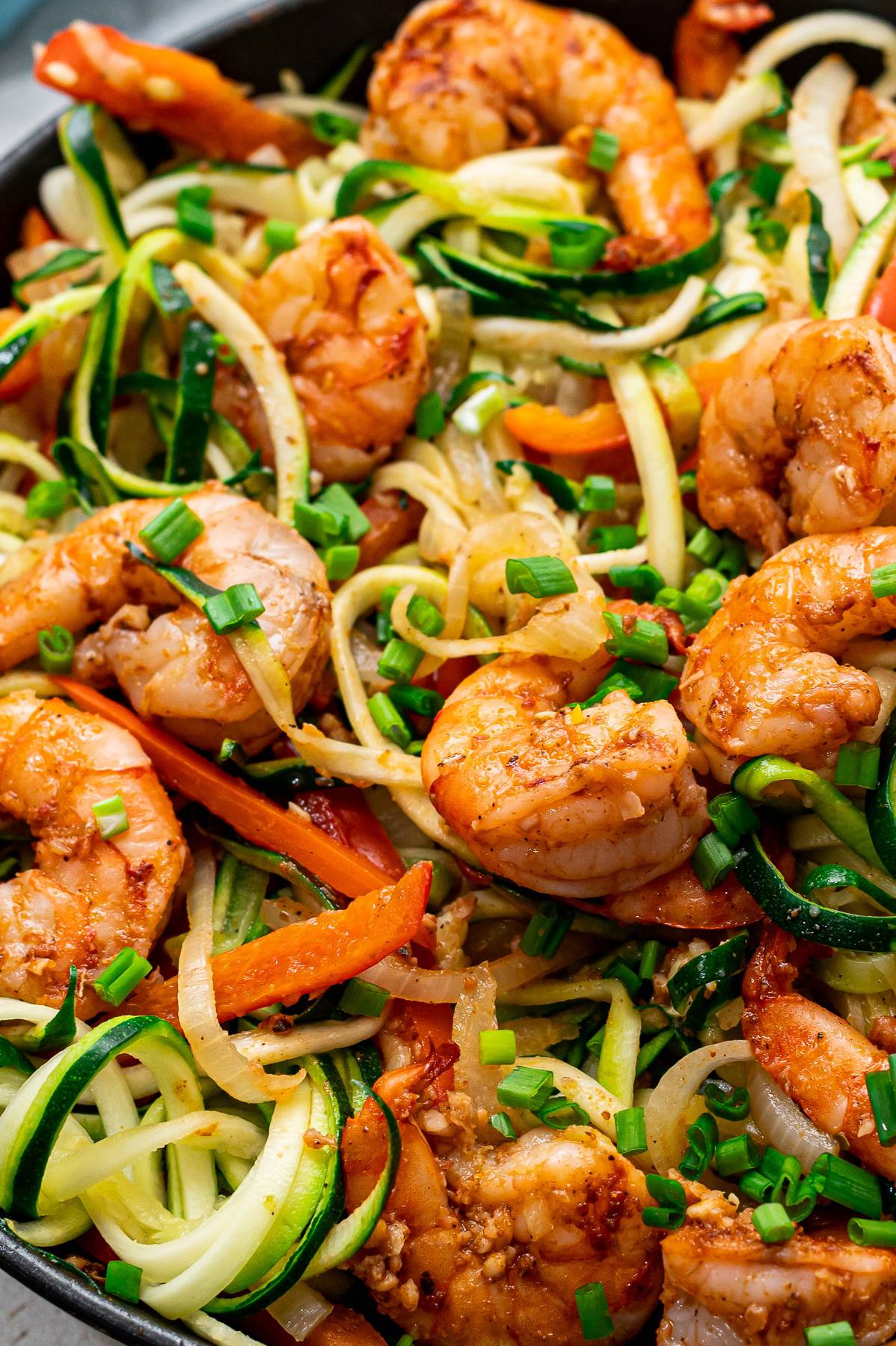 A close up view of shrimp and noodles with veggies.