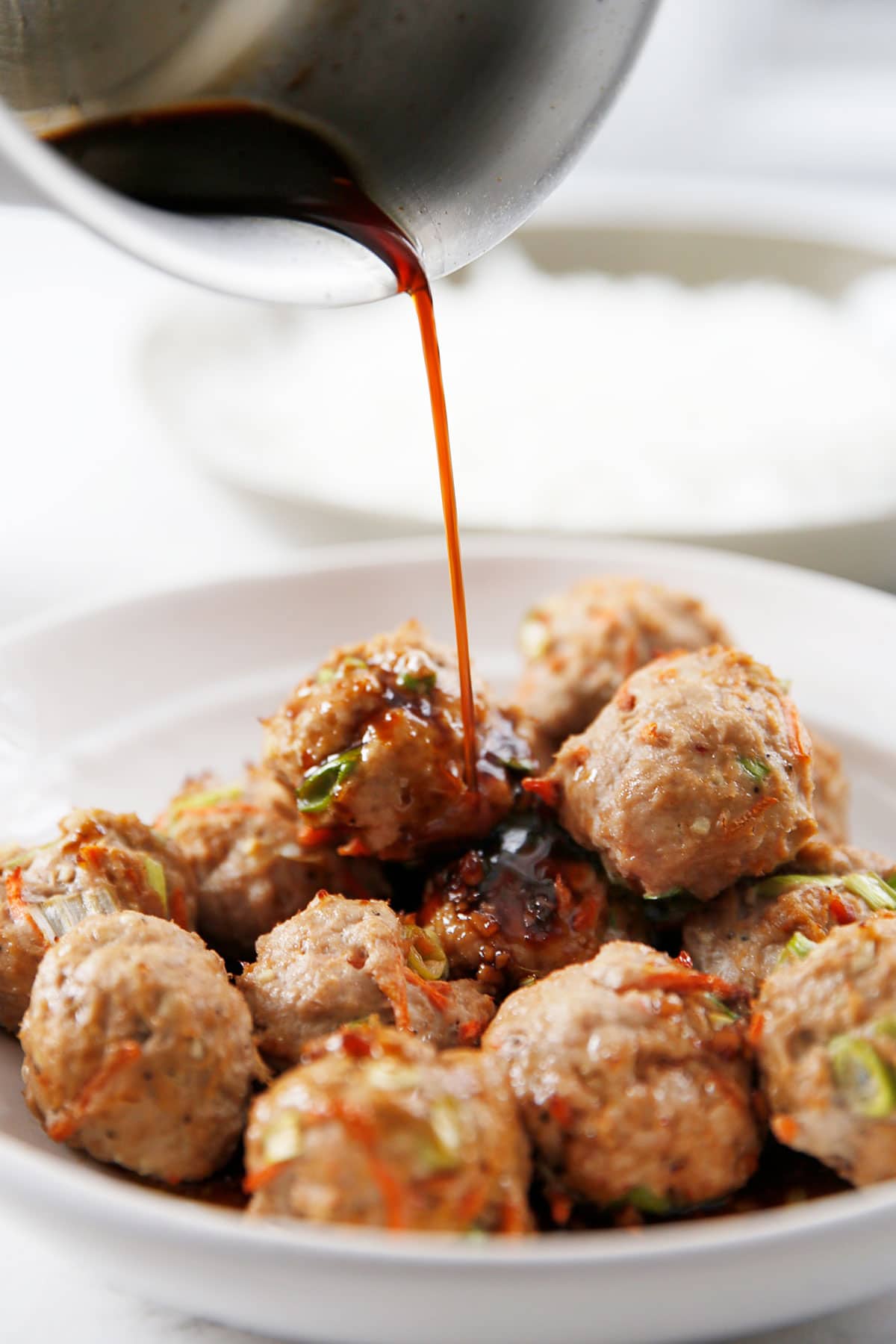 Pouring sauce over thai meatballs.