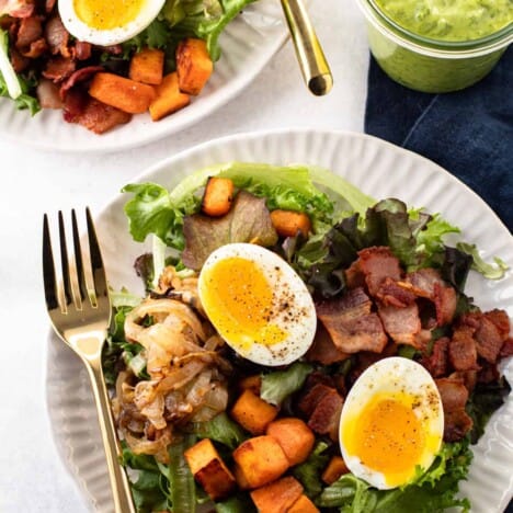 Breakfast salad with soft-boiled eggs, bacon, potatoes and onions.