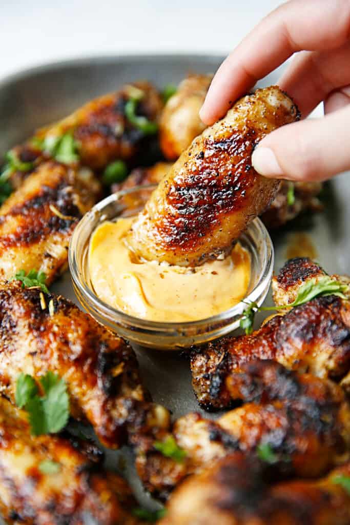 A dry-rub wing being dipped into a sauce.