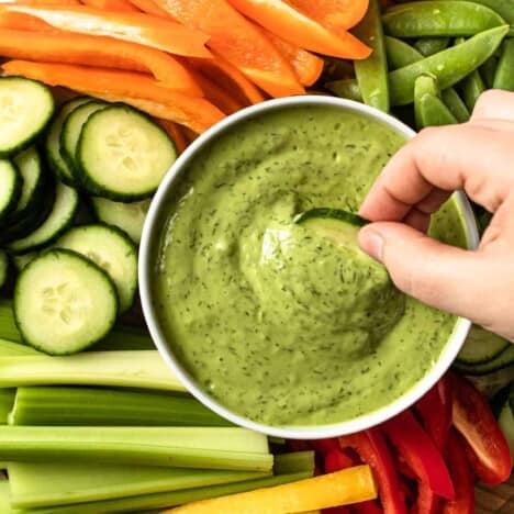 Green goddess dressing in a bowl surrounded by crudite.