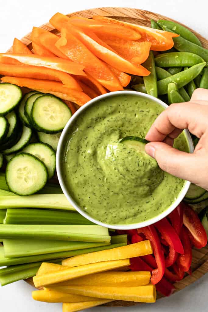 Green goddess dressing in a bowl surrounded by crudite.