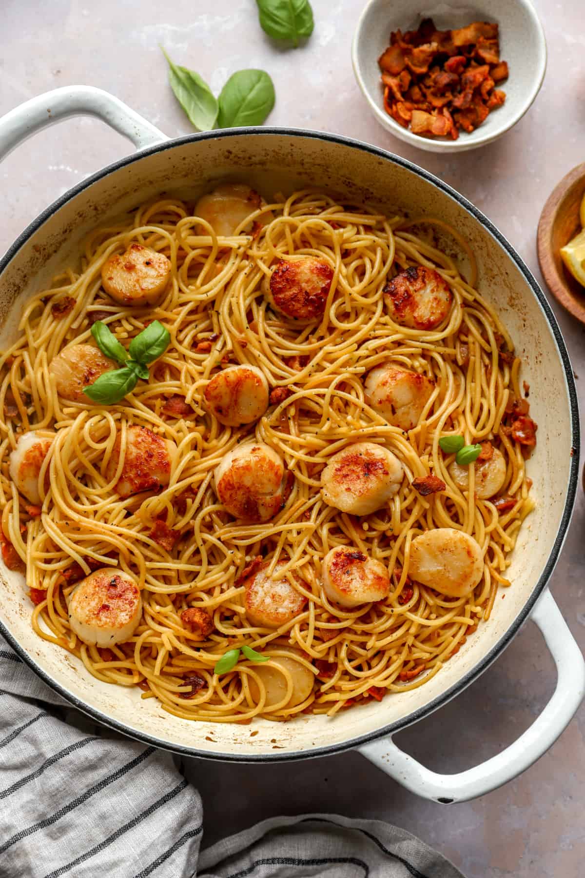 a large skillet from above filled with spaghetti and scallops and garnished with fresh basil.