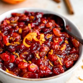 a bowl filled with cranberry relish topped with orange peel.