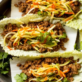 A plate with three asian cabbage wraps.