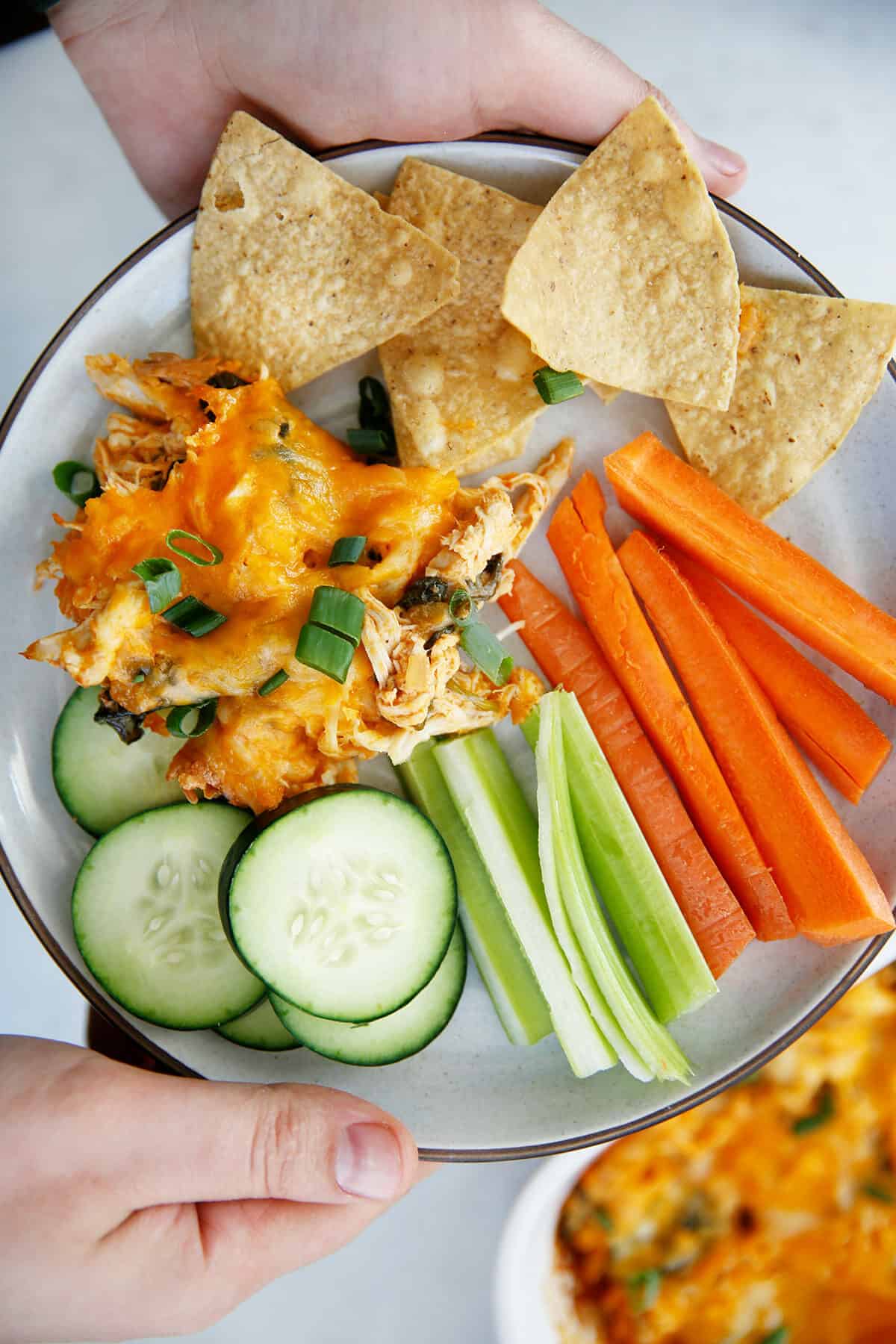 A plate of buffalo chicken dip with chips and veggies.