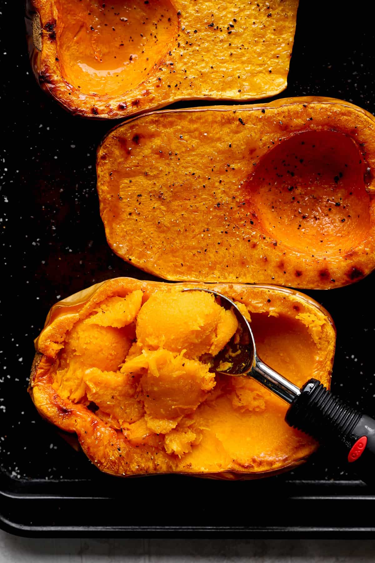 cooked squash flesh being scooped out of the peel.