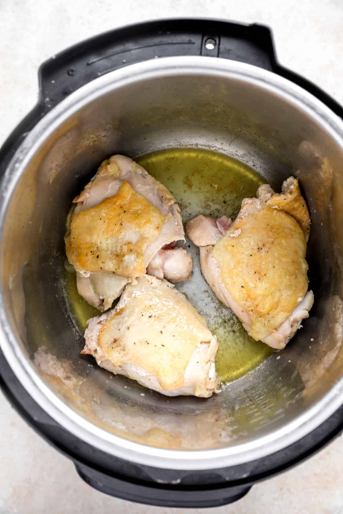 three pieces of chicken being seared in an instant pot.