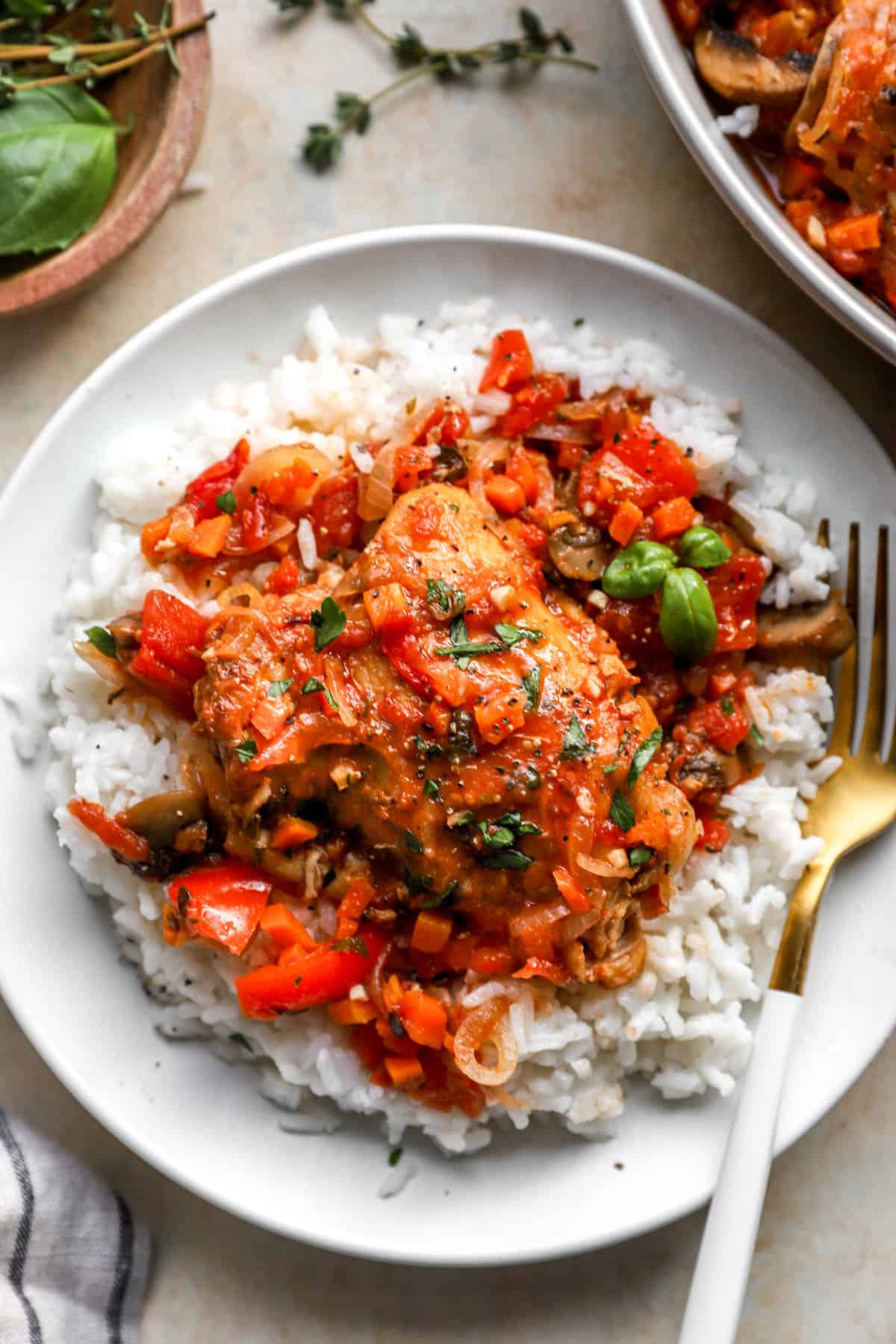 above image of a plate filled with chicken cacciatore over rice with a gold fork.