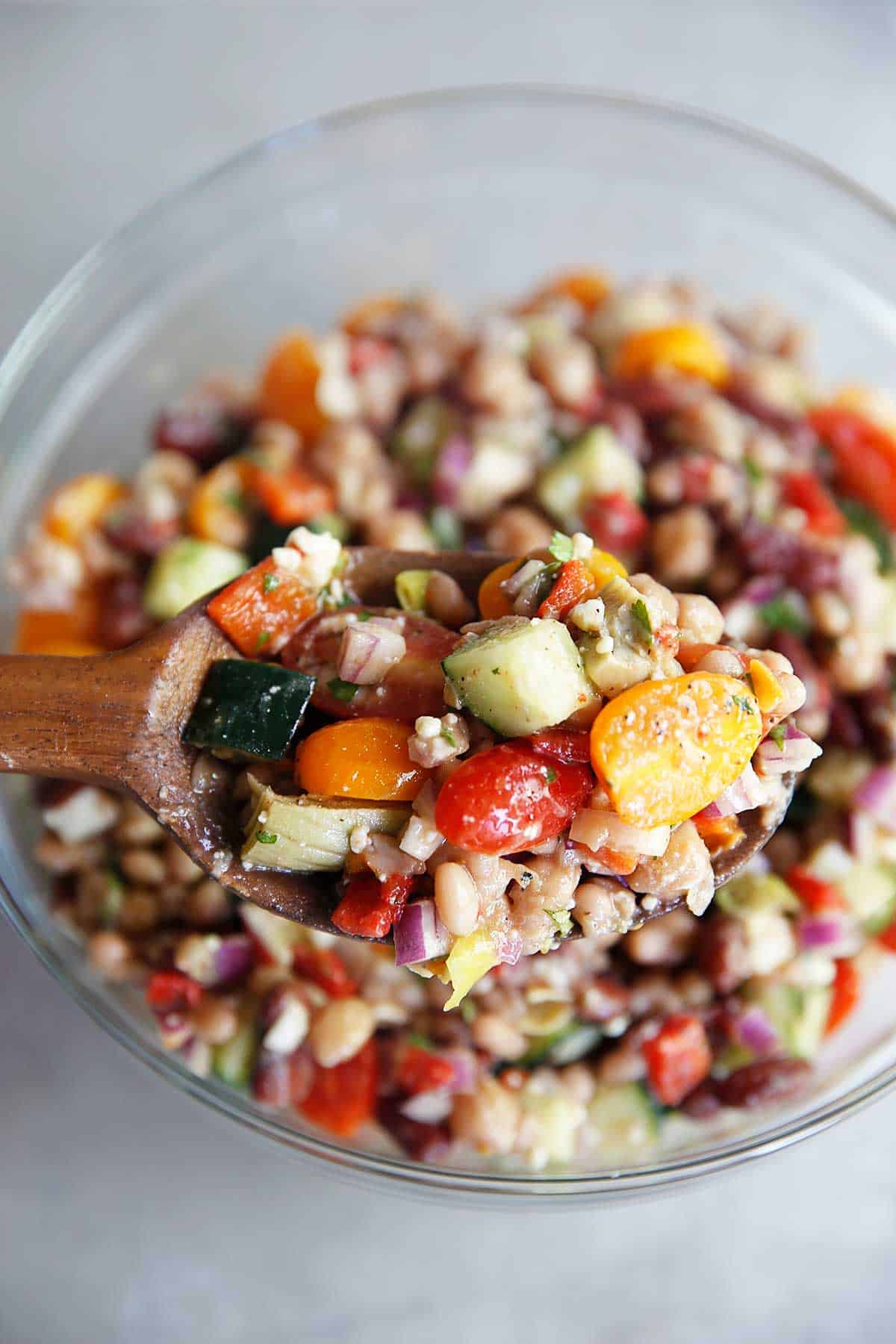 Greek Three Bean Salad with cucumber and tomatoes in a bowl.