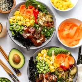 Pictured above are two poke bowls surrounded by toppings.