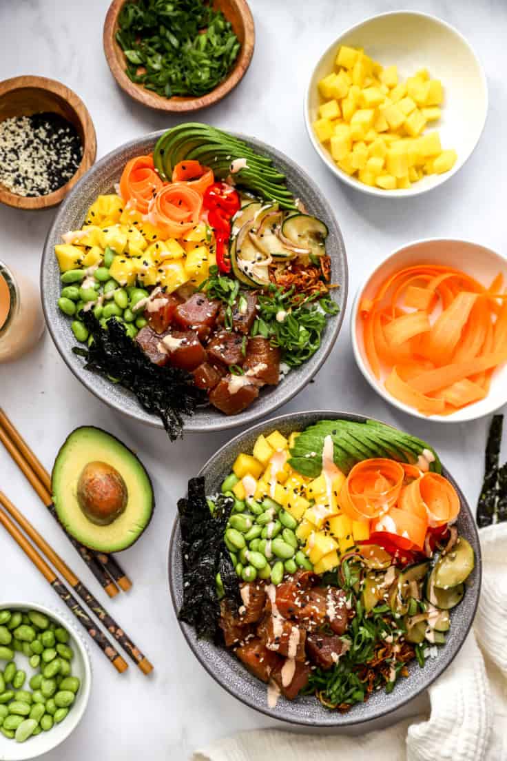 above image of two poke bowls surrounded by toppings.