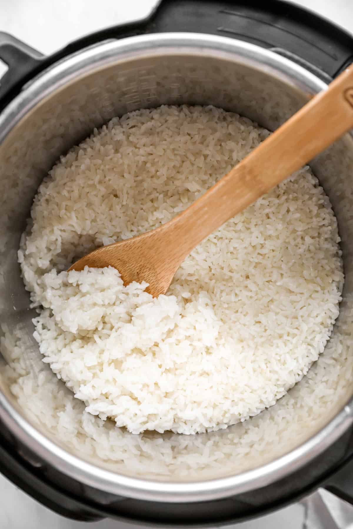 cooked sticky rice in the instant pot with a wooden spoon.