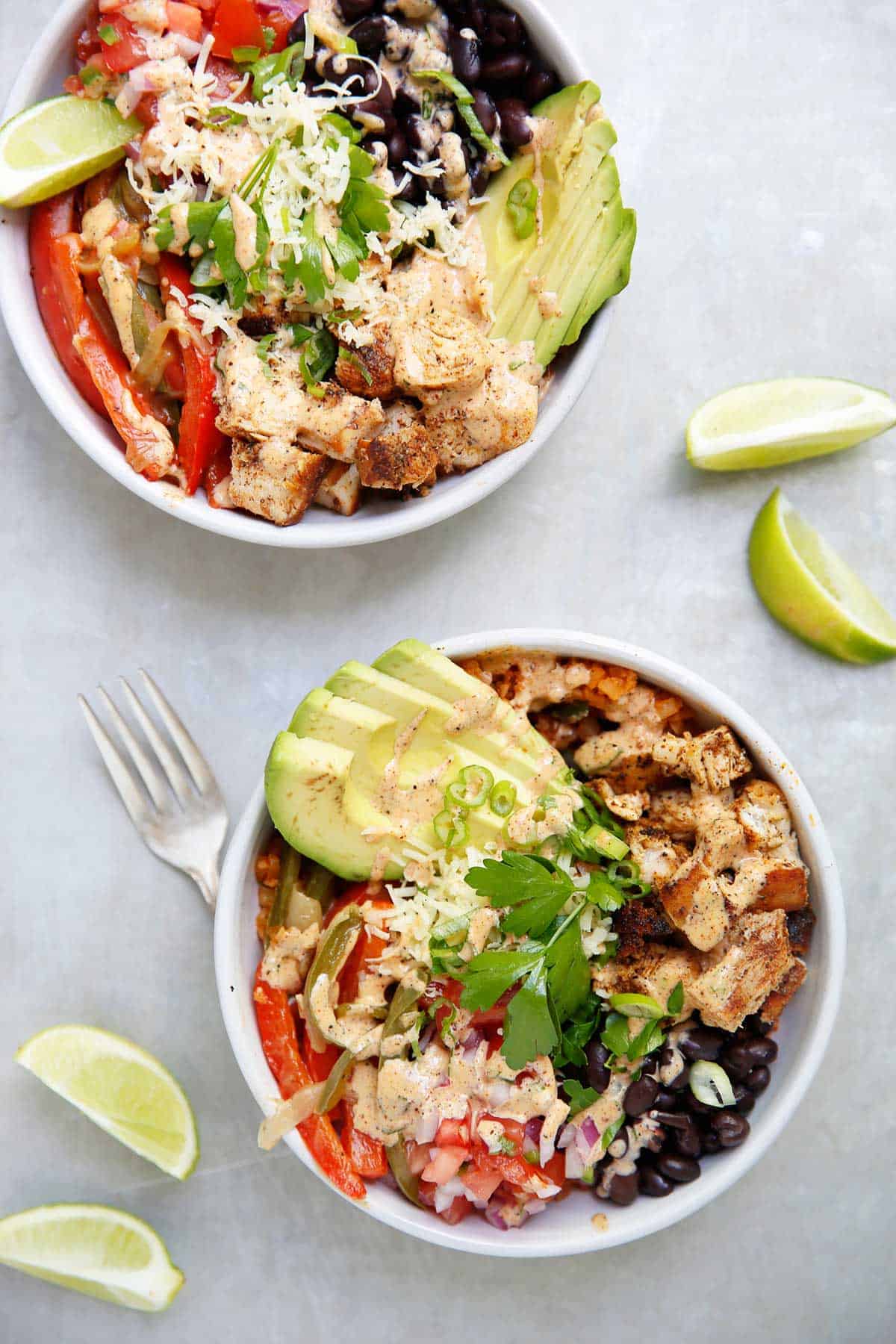 overhead of two assembled chipotle chicken burrito bowls.