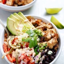 assembled chipotle chicken burrito bowl topped with cilantro and avocado.