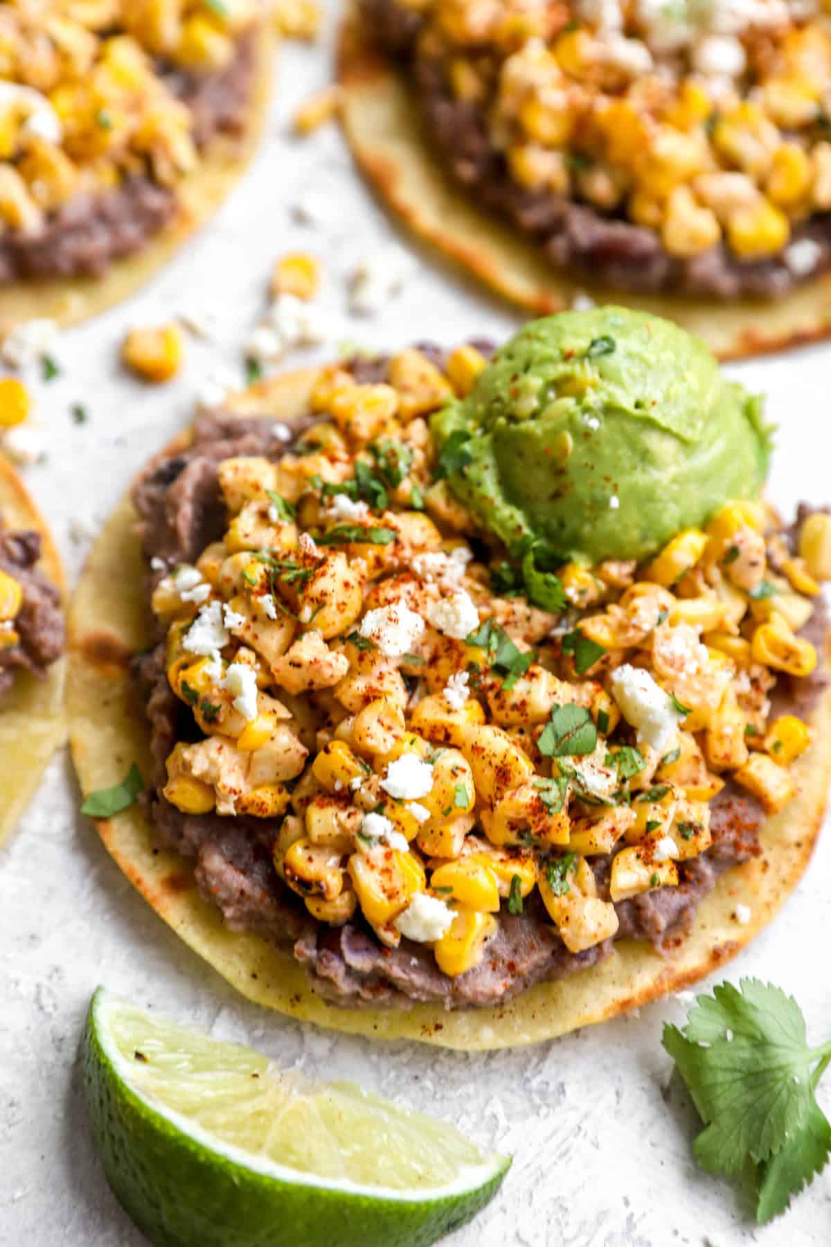 a tostada piled with Mexican corn salad and topped with avocado from above.