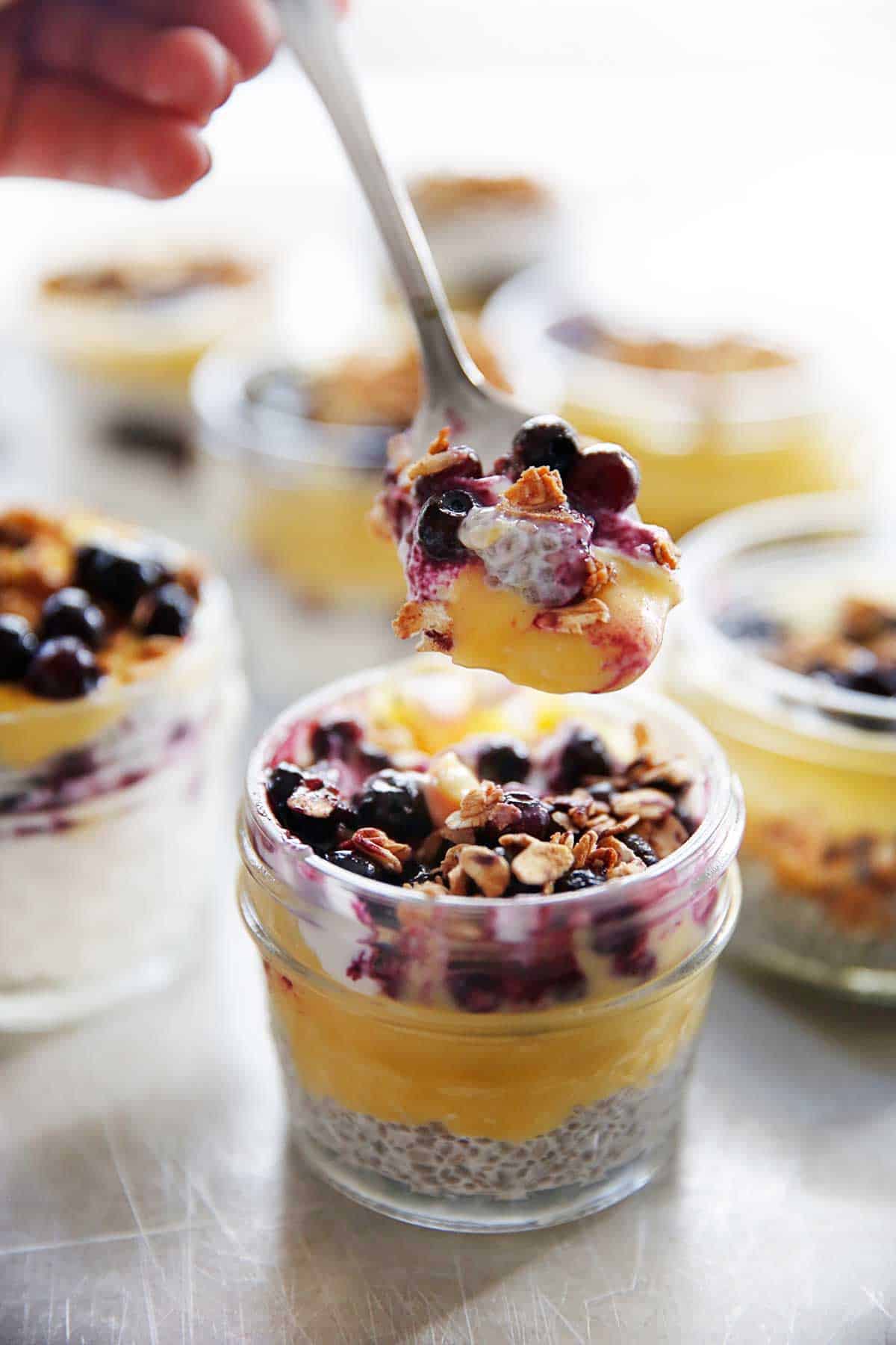 A spoonful of lemon and blueberry breakfast parfaits in a jar.