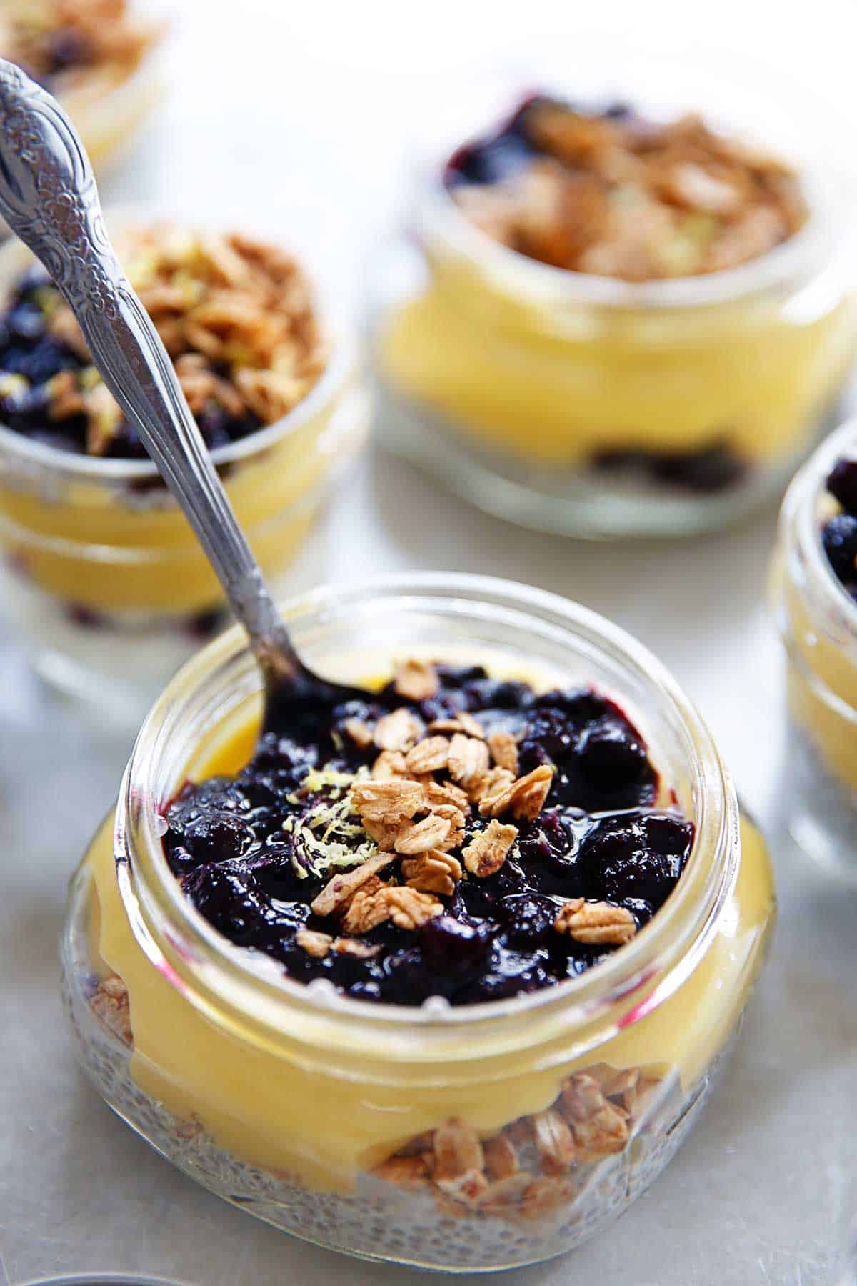 Lemon and blueberry breakfast parfaits in a jar with a spoon in it.
