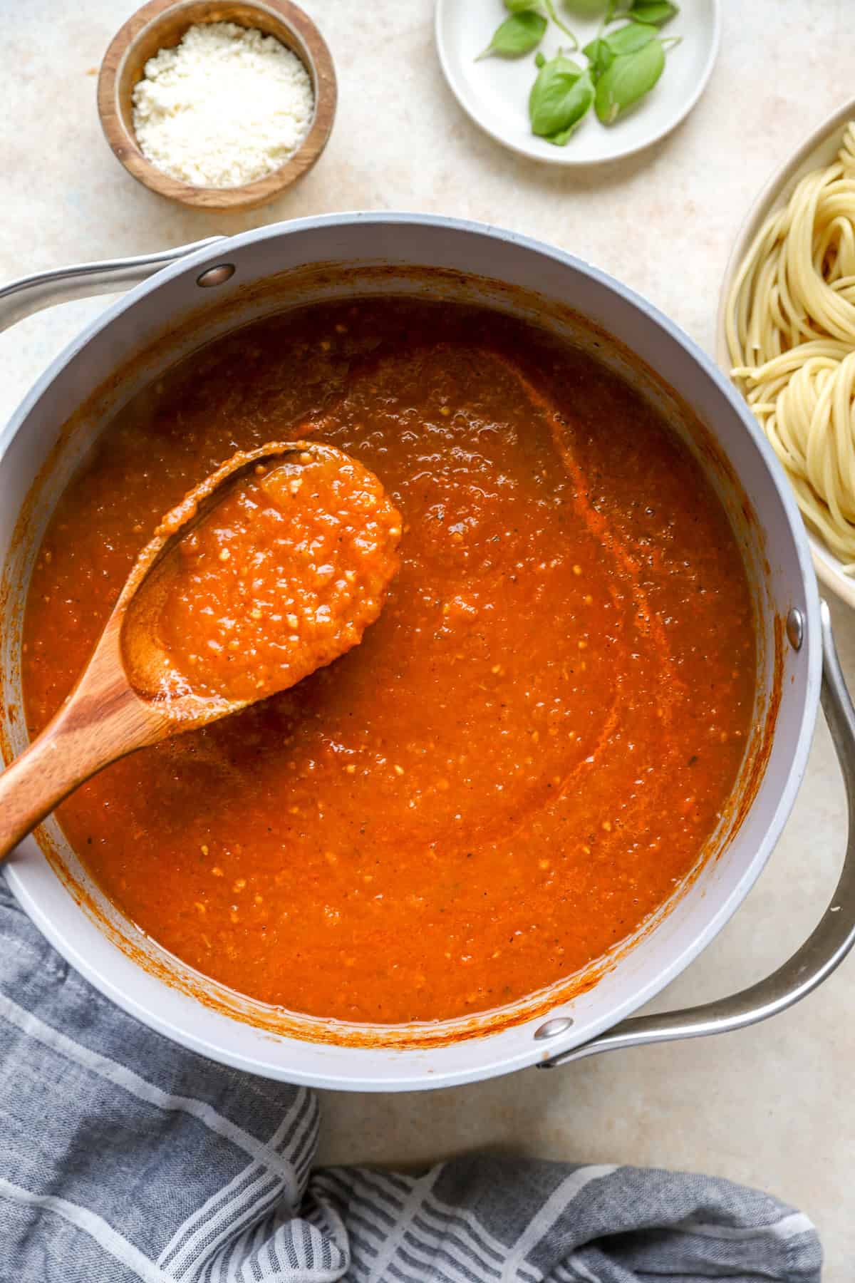 A stock pot full tomato sauce with a brown, wooden spoon, scooping the sauce. 