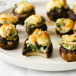 a platter filled with spinach dip stuffed mushrooms.