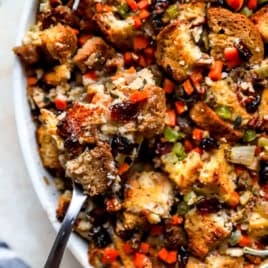Gluten-Free Stuffing in a white serving bowl with a silver spoon.