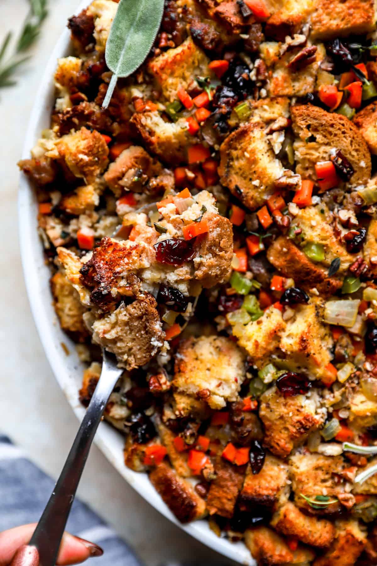 Gluten-Free Stuffing in a white serving bowl with a silver spoon.