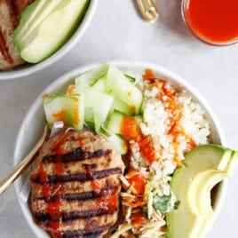 overhead shot of a bowl with a turkey burger, rice, slaw, and avocado.