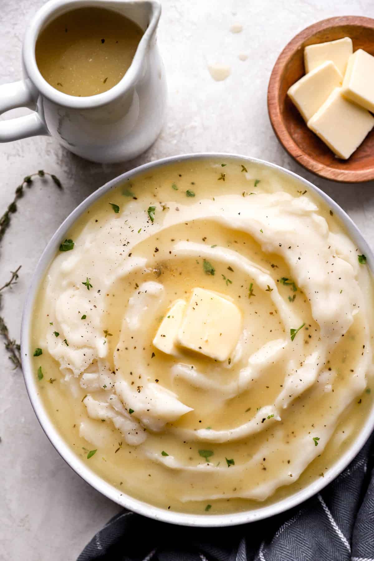 gluten free gravy pooled in a bowl of mashed potatoes topped with a pat of butter from above.